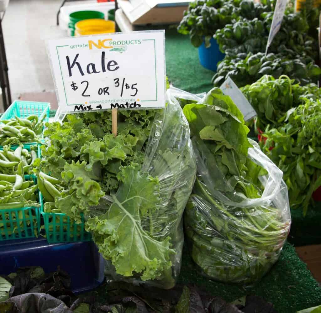 Fresh kale and greens displayed with price tags at a local NC farmers market.