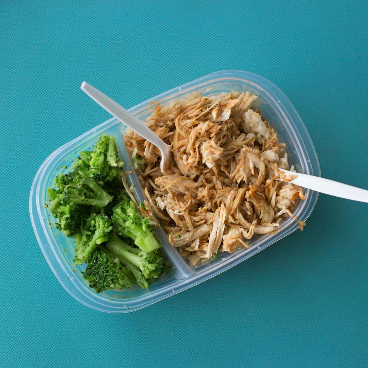 Delicious packed lunch with shredded chicken, rice, and broccoli in a tupperware container.