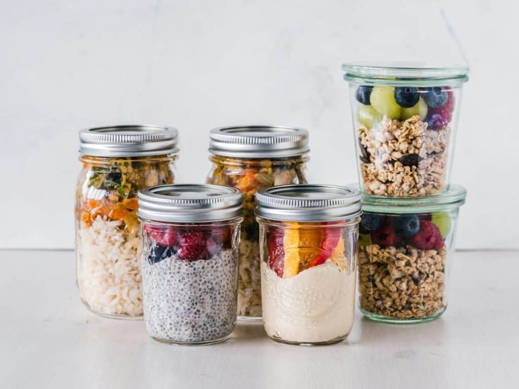 Close-up of healthy food jars containing granola, fruits, and yogurt.