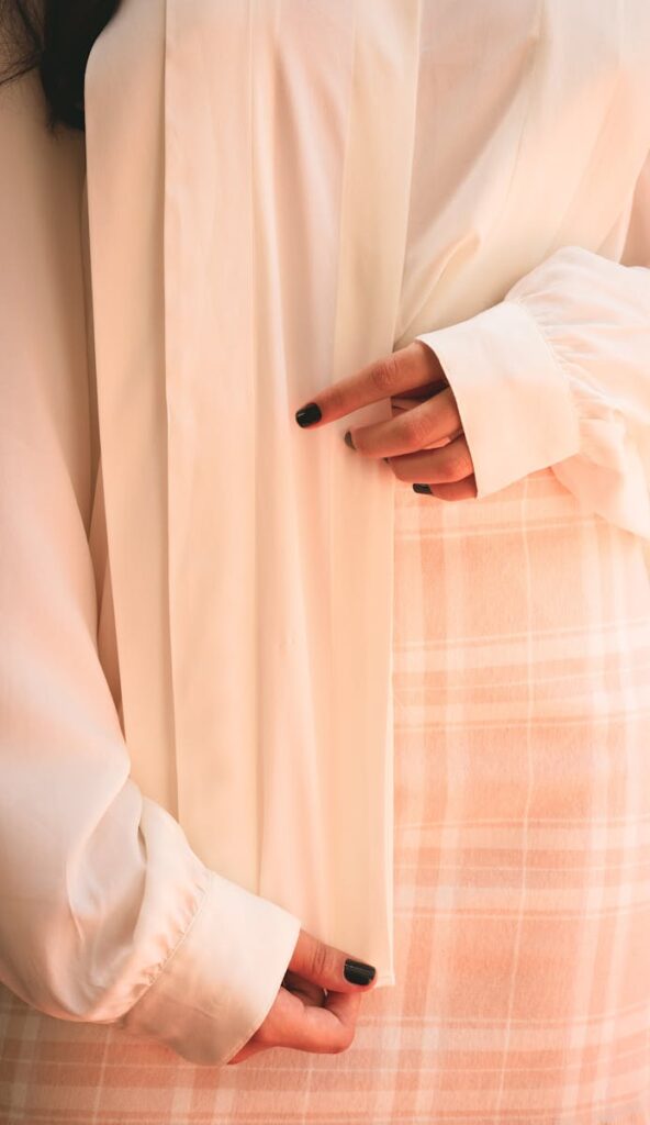 A close-up shot of a woman's hands showcasing elegant attire with soft tones and textures.