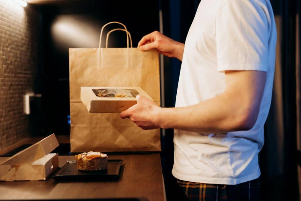 Man unpacking a food delivery bag in a modern kitchen. Ideal for lifestyle or delivery themes.