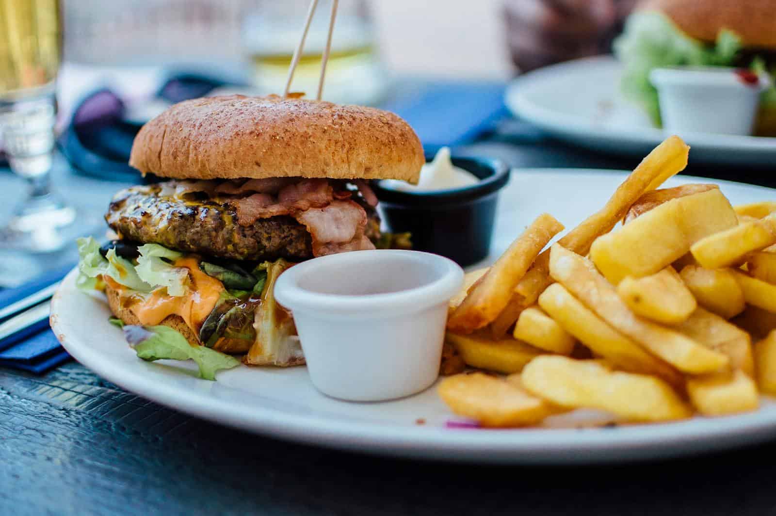 Close-up of a juicy burger and crispy fries served with sauces, perfect for a hearty meal.