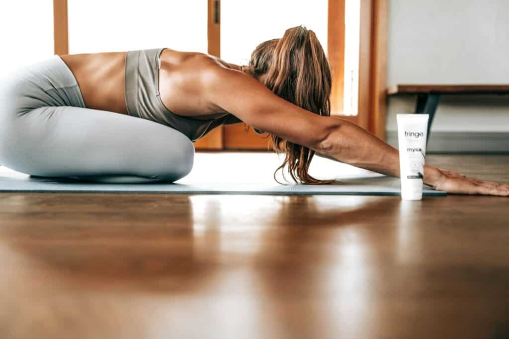 woman in gray sports bra and gray leggings lying on floor